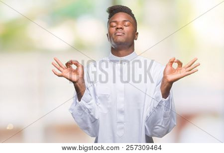 Young arabic african man wearing traditional djellaba over isolated background relax and smiling with eyes closed doing meditation gesture with fingers. Yoga concept.