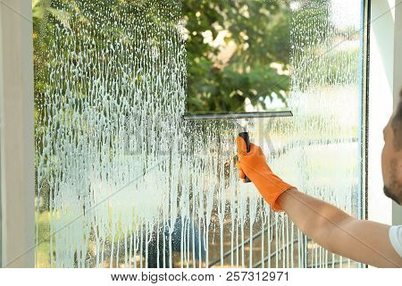 Male Janitor Cleaning Window With Squeegee, Closeup