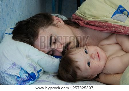 Little Baby Girl Wake Up In The Morning. Parent Tired Sleeping. Father Lying On Bed. Happy Family.