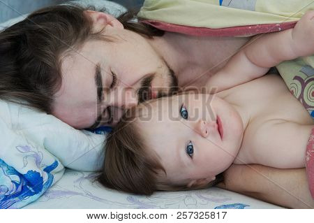 Little Baby Girl Wake Up In The Morning. Parent Tired Sleeping. Father Lying On Bed. Happy Family.