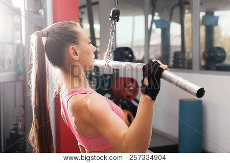 Athletic Girl With A Ponytale Wearing Pink And Black Professional Sportswear Exercising With An Iron