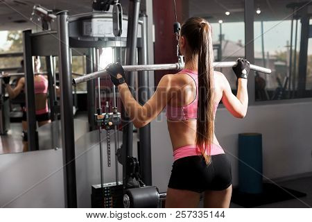 Sexy Woman With A Ponytale Wearing Pink And Black Professional Sportswear Doing Exercises With An Ir