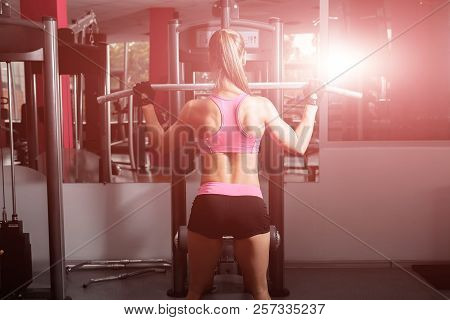 Woman With A Ponytale Wearing Pink And Black Professional Sportswear Doing Exercises With An Iron Ba