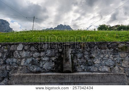A Water Fountain In The Village Of Santa Fosca, In The Italian Dolomites On A Summer Morning.