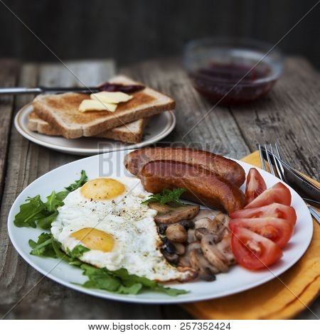 English Breakfast. Eggs, Sausages, Mushrooms, Tomatoes, Toast Bread. Eating Tasy Food Over Rustic Wo