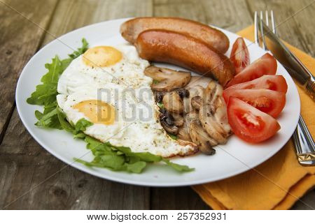 English Breakfast. Eggs, Sausages, Mushrooms, Tomatoes, Toast Bread. Eating Tasy Food Over Rustic Wo