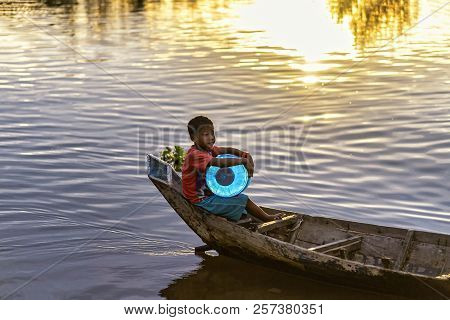Tonle Sap, Cambodia - January 04, 2017: A Young Boy On A Canoe Carries A Can Of Water In The Tonle S