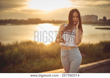 Young Beautiful Caucasian Girl Listening To Music With Smartphone Walking In The City With Headphone