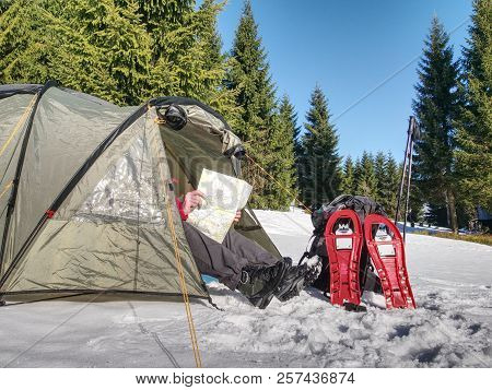 Hiker Prepare Equipment For Snowshoes Trip. Winter Few Days Trek In Snowy Mountains. Light Green Ten