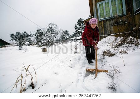 Elderly woman cleans snow near the his house at vinter.