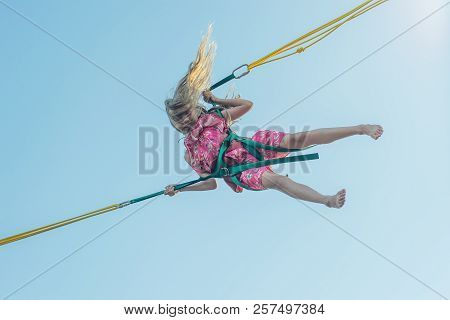 A Girl In A Multicolored Dress Falls Down On An Attraction Against The Sky. A Fascinating Attraction
