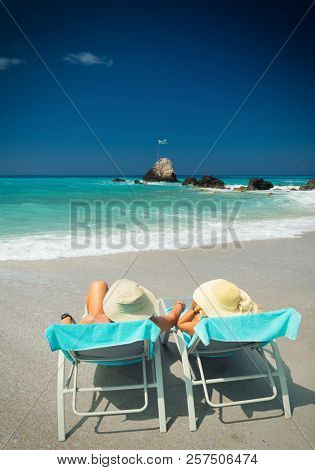 Couple on sunbeds relaxing at the beach in Lefkada Greece