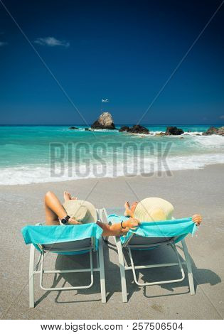 Couple on sunbeds relaxing at the beach in Lefkada Greece
