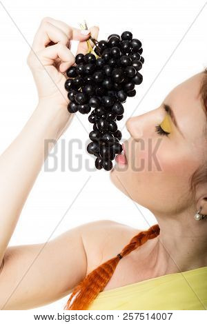 Beautiful Redhead Woman Is Eating Black Grapes. Concept Of Healthy Eating