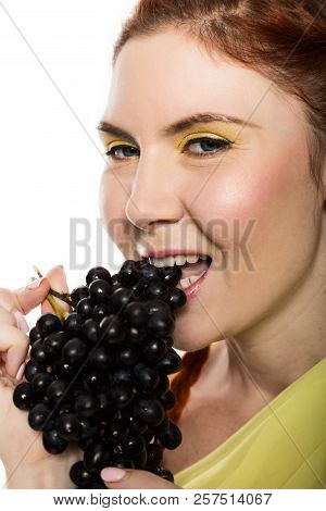 Beautiful Redhead Woman Is Eating Black Grapes. Concept Of Healthy Eating