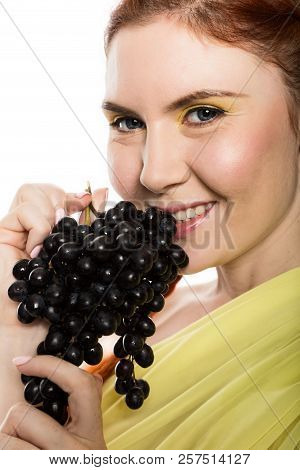 Beautiful Redhead Woman Is Eating Black Grapes. Concept Of Healthy Eating