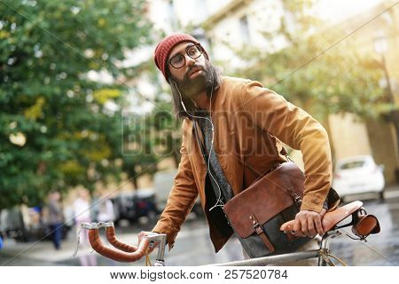 Hipster guy in town using earphones and fixie bike