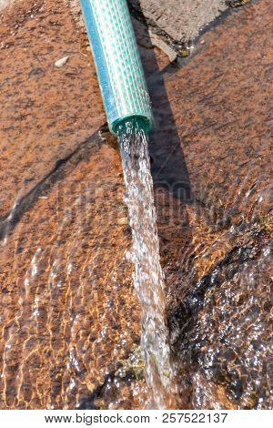 A Close Up View Of Water Spraying Out A Burst Pipe Under The Ground In An Outside Garden
