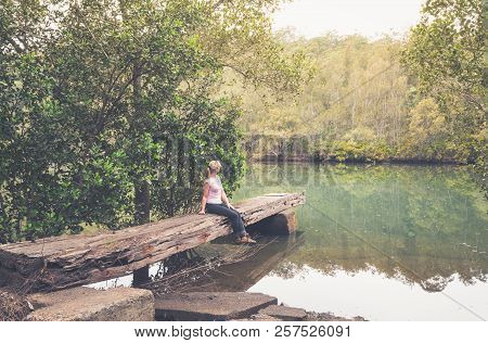 Sitting On A Rustic Large Hewn Timber Jetty Very Worn And Weathered In Remote Bushland Creek Austral
