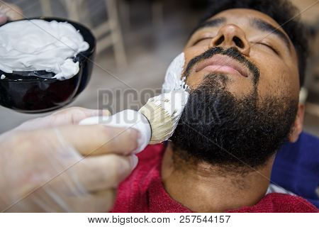 Young Black Man Shaving Beard In Barbershop