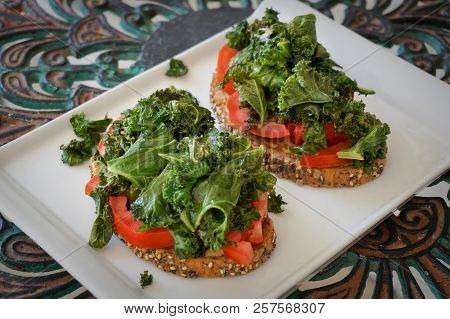 Vegan Toasts With Kale,  Tomato, Tahin And Rye Bread On White Plate