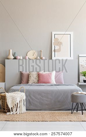 Hairpin Pouf With Book And Knit Blanket In Wicker Basket Standing On Carpet By The King-size Bed In