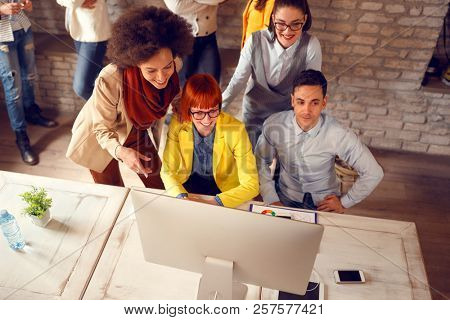 Group of young people looking at computers screen in office 