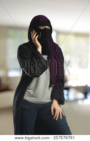 Arabic woman wearing a burqa on the cell phone inside a building