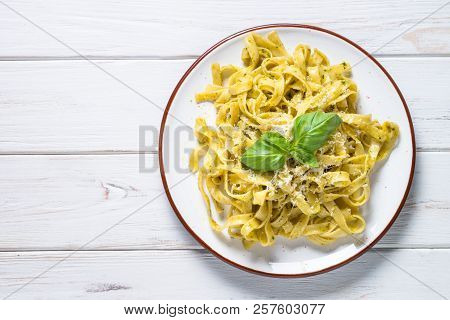 Tagliatelle Pasta With Pesto Sauce And Parmesan Cheese On White Wooden Table. Top View, Copy Space.