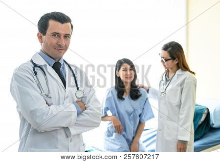 Portrait Of Profressional Doctor With Stethoscope While Female Doctor Take Care Her Patient.