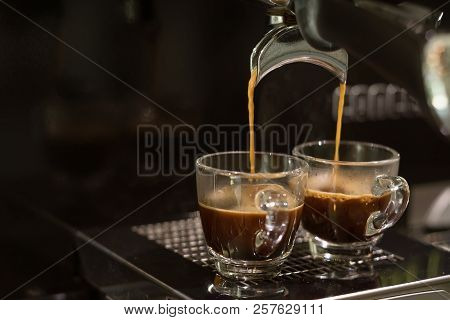 Closed-up Espresso Machine Brewing Coffee In Two Shot Glasses Throgh Portafilter