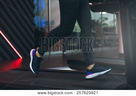 Legs Of Sportsman Woman Running On A Treadmill: Sport And Healthy Lifestyle Concept. Legs Of An Athl