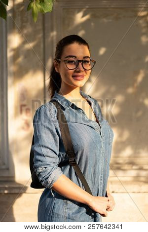 Young Attractive Bespectacled Woman Looking At The Camera And Smiling.