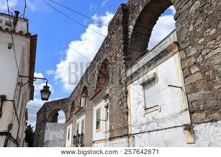 Evora Town In Portugal. Unesco World Heritage Site. Prata Aqueduct With Homes Beneath Arches.