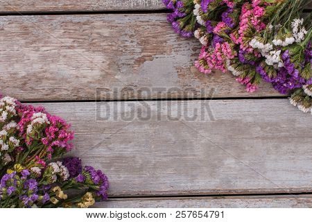 Statice Mix Color Limonium Sinuatum Flowers. Old Vintage Wooden Desk Surface Background.