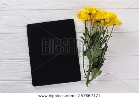 Tablet Device And Bouquet Of Sunchoke Flowers. Top View. White Wooden Background.