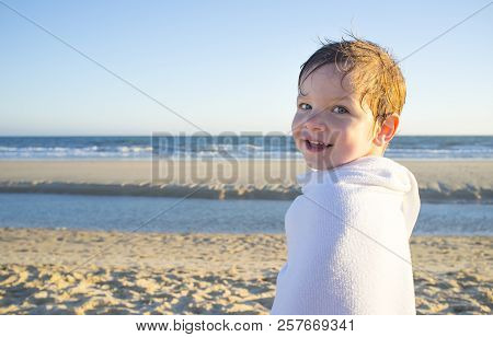 Smiling Little Boy Wrapped In A Towel After Swiming. Sunset Shot