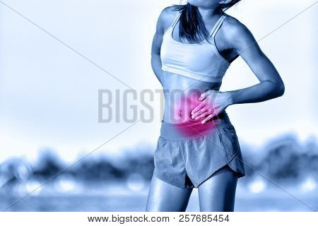 Stomach pain side stitch ache woman runner having cramp during workout running on beach. Female athlete with stomach side pain during jogging.