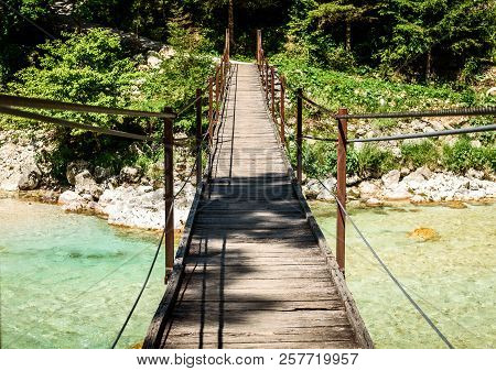 Wooden Hanging Bridge Leading Forward Over Green Mountain River.