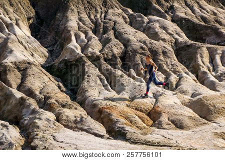 Young Slender Athletic Girl Runs Along A Rough, Deserted Mountainous Terrain