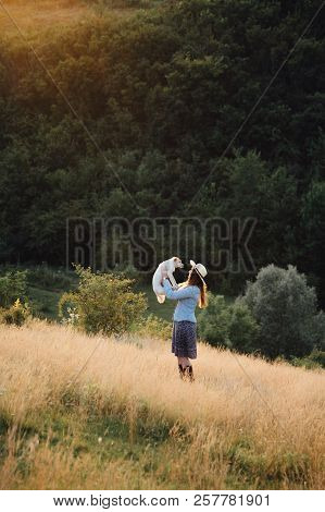 Girl In A Hat Playing With A Dog In The Field At Sunset Sun