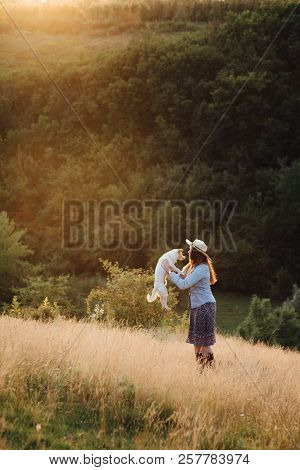 Girl In A Hat Playing With A Dog In The Field At Sunset Sun