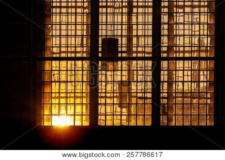 Last Sunlight From The Setting Sun Radiates Atmospherically Through Stained Glass Windows Of An Old 