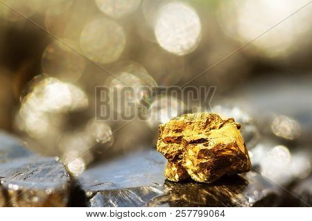 Golden Bar On Raw Coal Nuggets With Soft Focus And Shiny Background