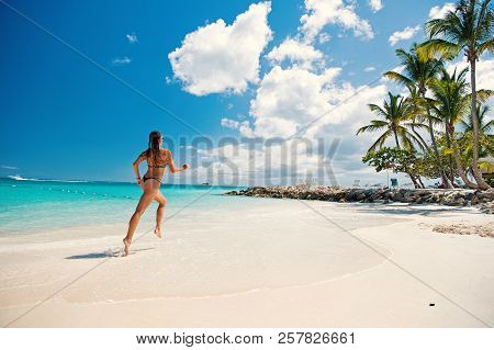 Young Pretty Woman With Beautiful Body In Swimsuit Running In Ocean Water Sunny Day At Tropicl Beach