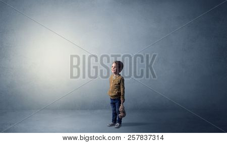 Little waggish kid staying alone in a big empty room with his plush