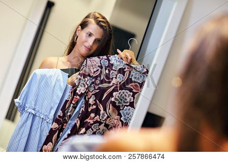 Beautiful woman thinking what to dress in walk-in closet