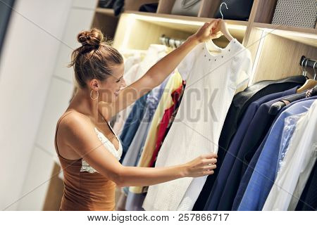 Beautiful woman thinking what to dress in walk-in closet