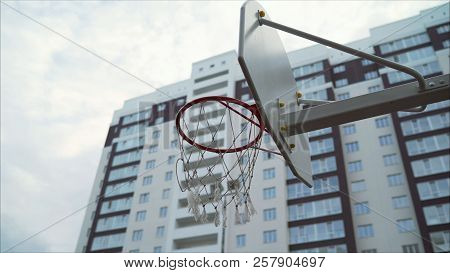 Basketball Ring In The Courtyard Of A Multi-storey Building. A New Basketball Ring With A Net.