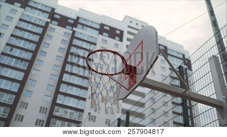 Basketball Ring In The Courtyard Of A Multi-storey Building. A New Basketball Ring With A Net.